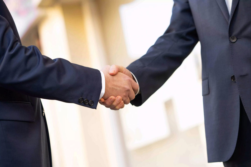 Ein Handschlag vor dem Büro von Kopp ImmobilienService in Berlin